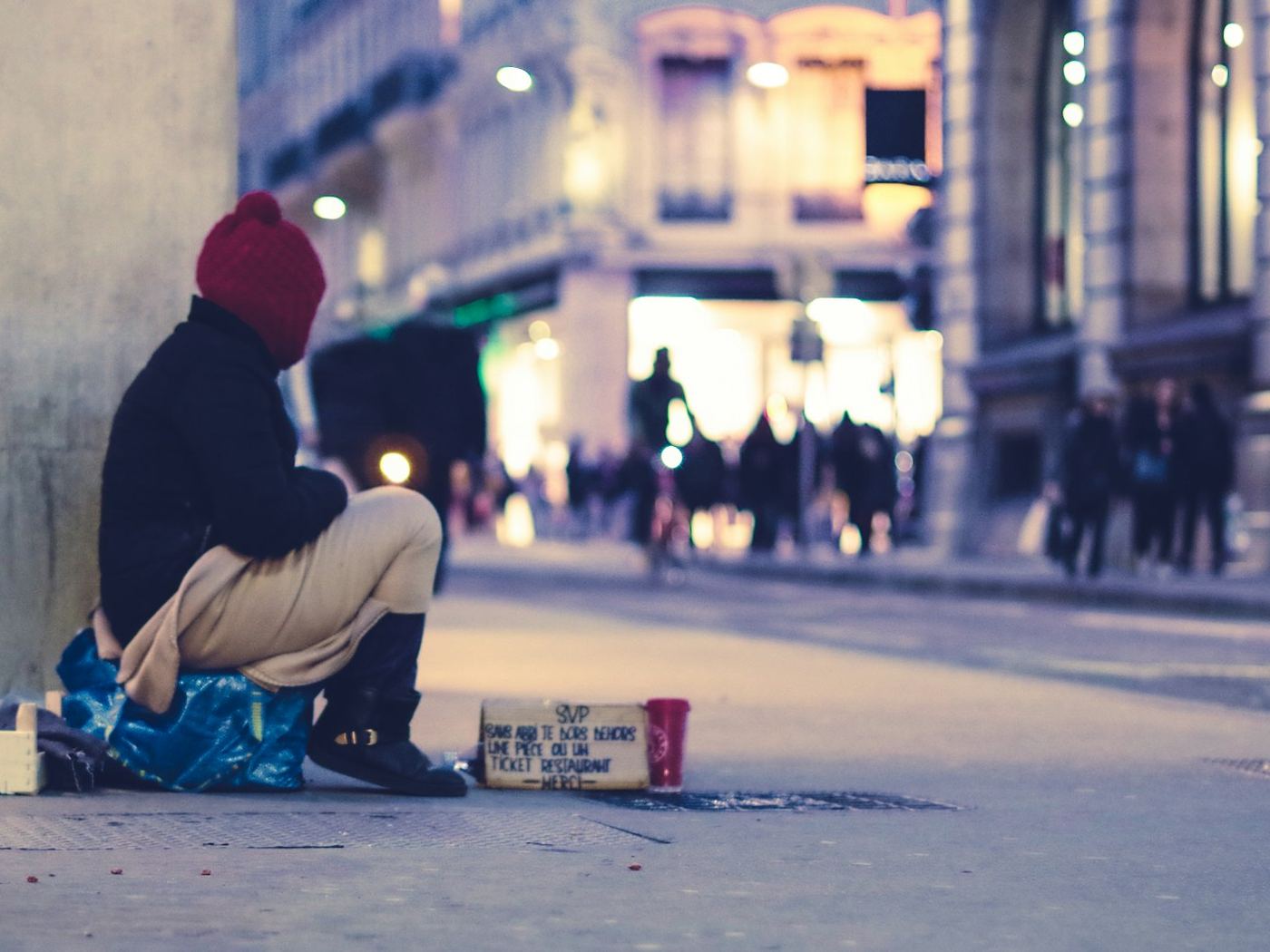 Une personne assise dans la rue, le soir, en ville
